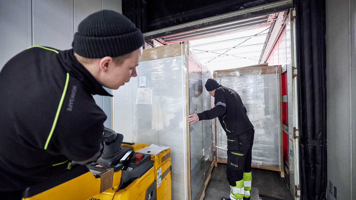 Bilde som viser to ansatte på vårt lager, som er i ferd med gjøre klar en forsendelse av garderobeskap på en lastebil.